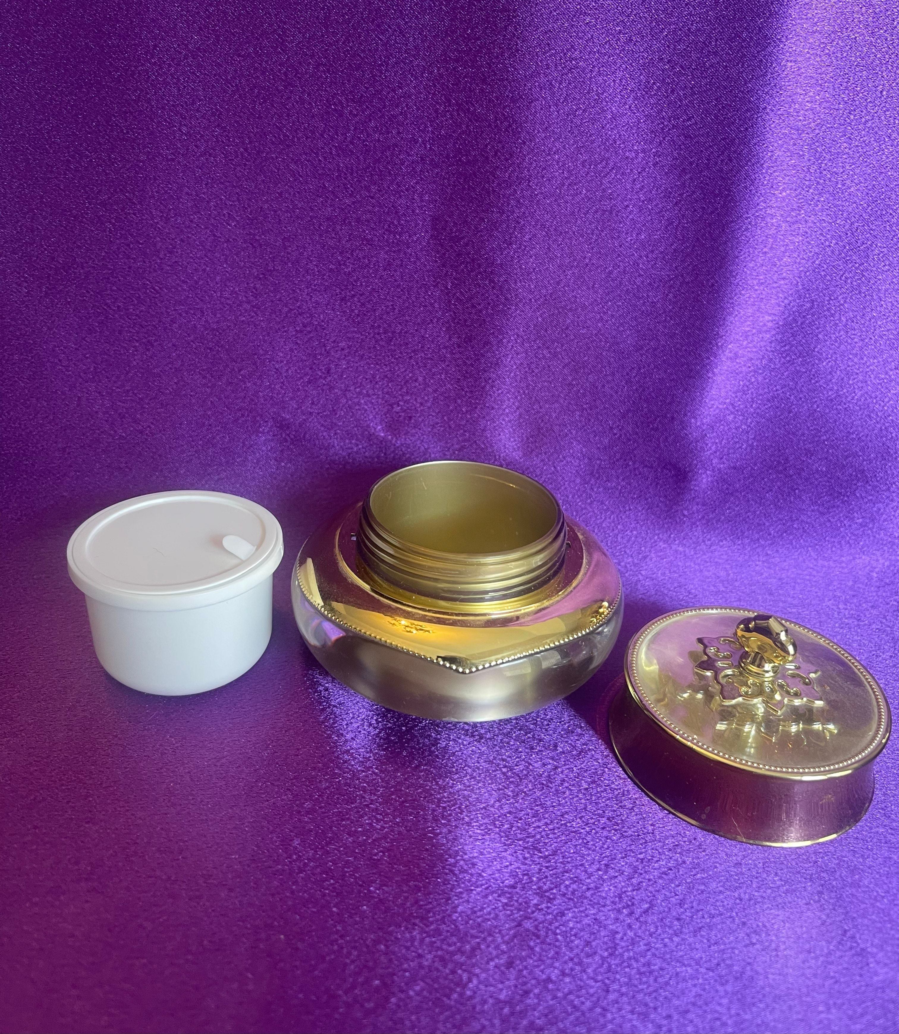 Three decorative containers with gold accents on a purple fabric background