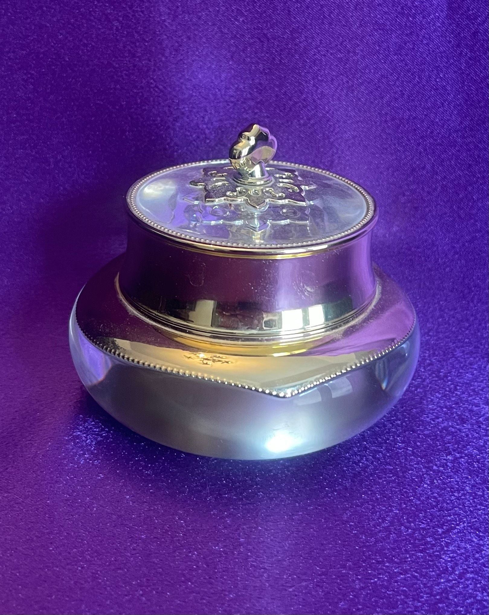 Silver container with a lid on a purple background